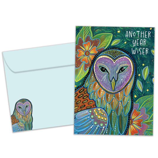 Front view of a birthday greeting card featuring an artistic and colourful illustration of an owl and foliage with the message "another year wiser", with a matching envelope.