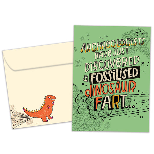 Front view of a Birthday greeting card with a green background and a funny message about a fossilised dinosaur fart, with a matching envelope.