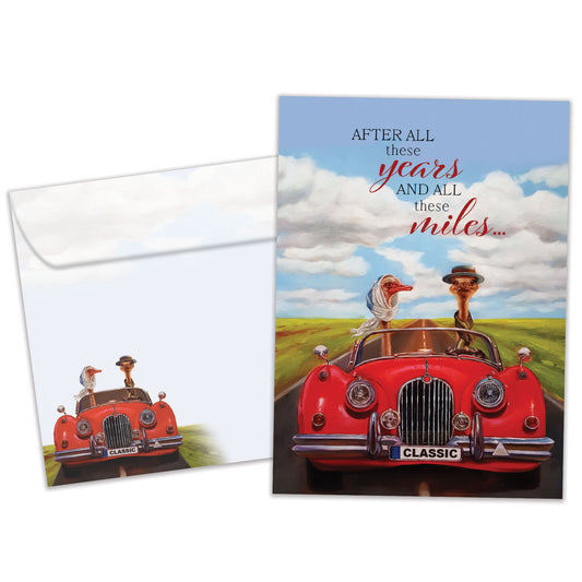 Front view of an Anniversary greeting card and matching envelope featuring a goose couple driving in a red car with a loving message.