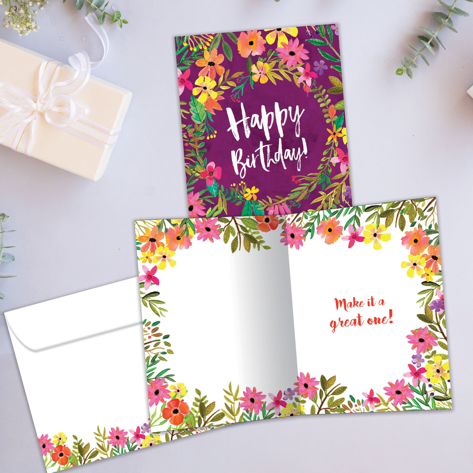 Front and inside view of a birthday card showcasing "Happy Birthday" surrounded by flowers on a purple background, with a matching envelope.