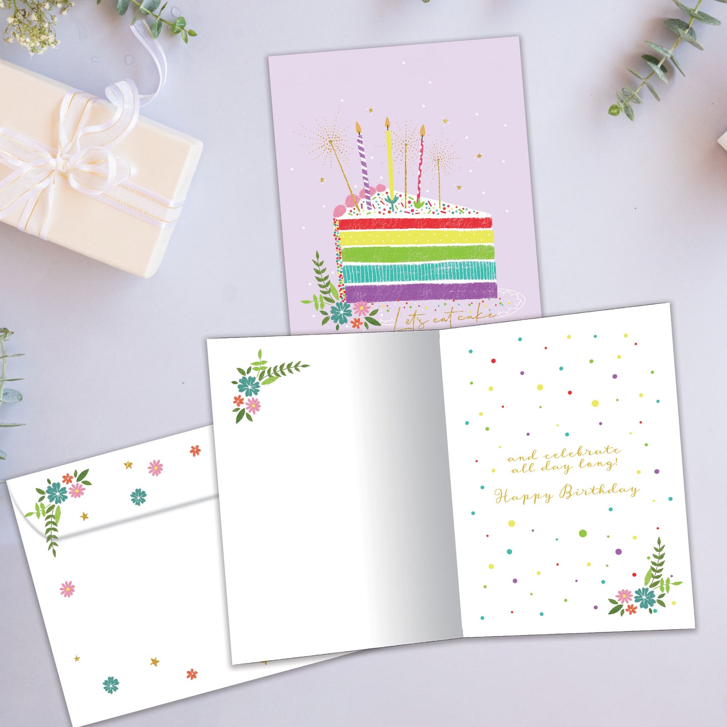 Front and inside view of a Birthday greeting card showcasing a colourful cake slice with the words "let's eat cake", with a matching envelope.