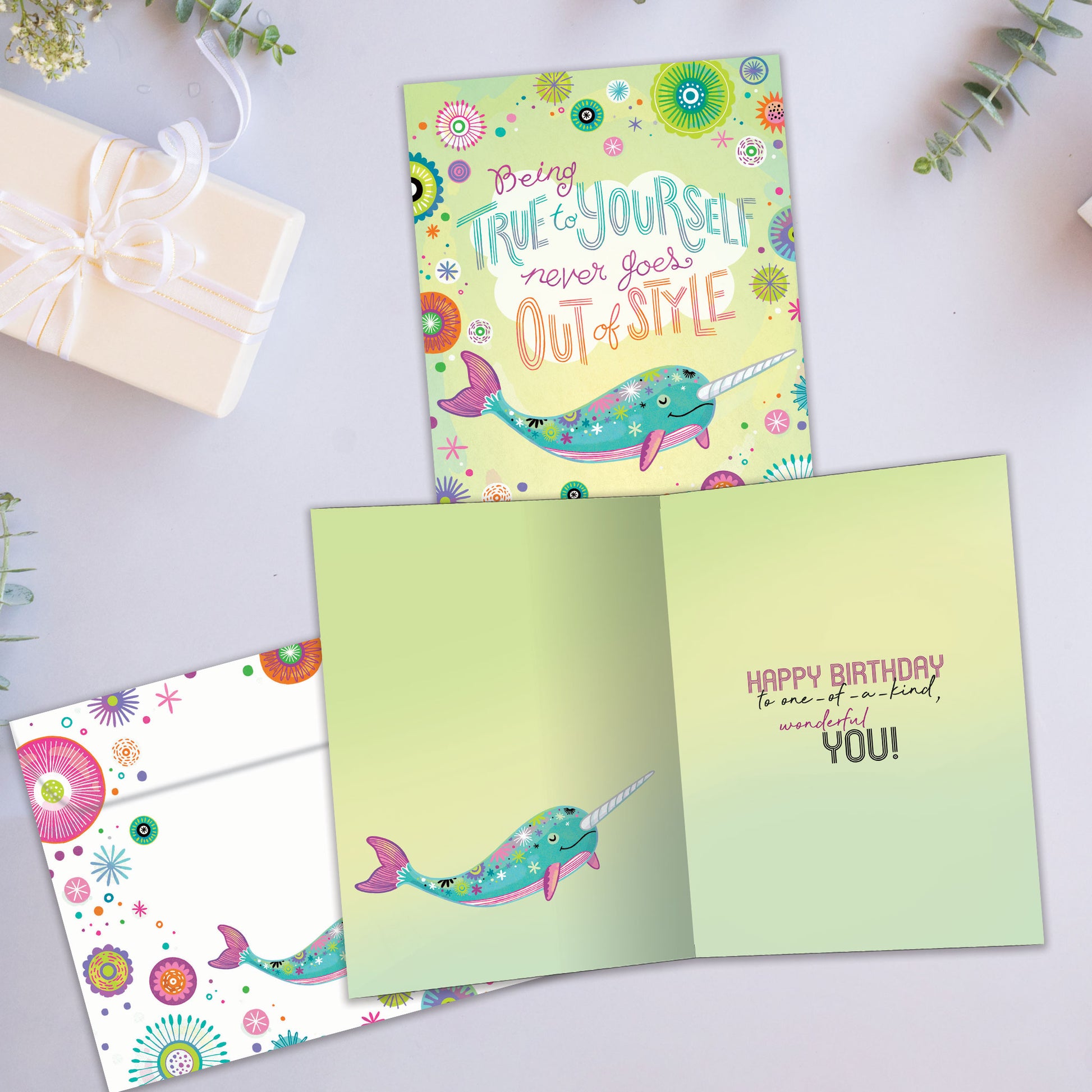 Front and inside view of a Birthday greeting card showcasing a pastel-colored narwhal with a message about being true to yourself, with a matching envelope.