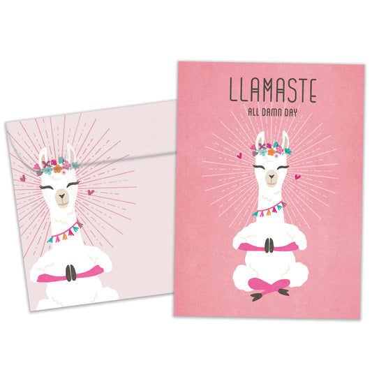Front view of a Birthday greeting card featuring a meditating llama on a pink background with the message "Llamaste all damn day", with a matching envelope.