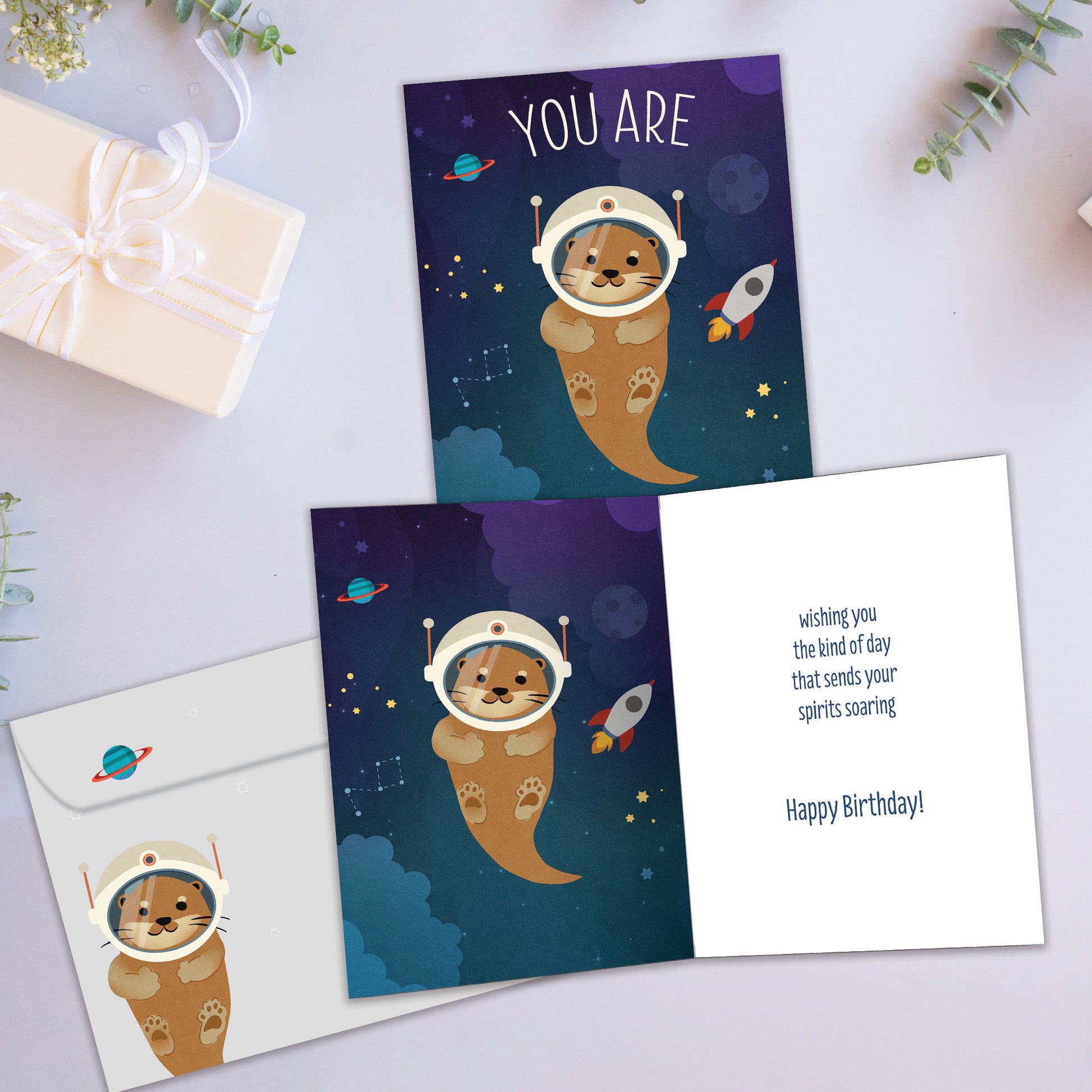 Front and inside view of a Birthday greeting card showcasing an otter in space with the message "You are otter this world!", with a matching envelope.