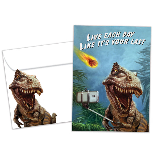 Front view of a Birthday greeting card featuring a dinosaur taking a selfie with a fireball flying towards it, with a matching envelope.