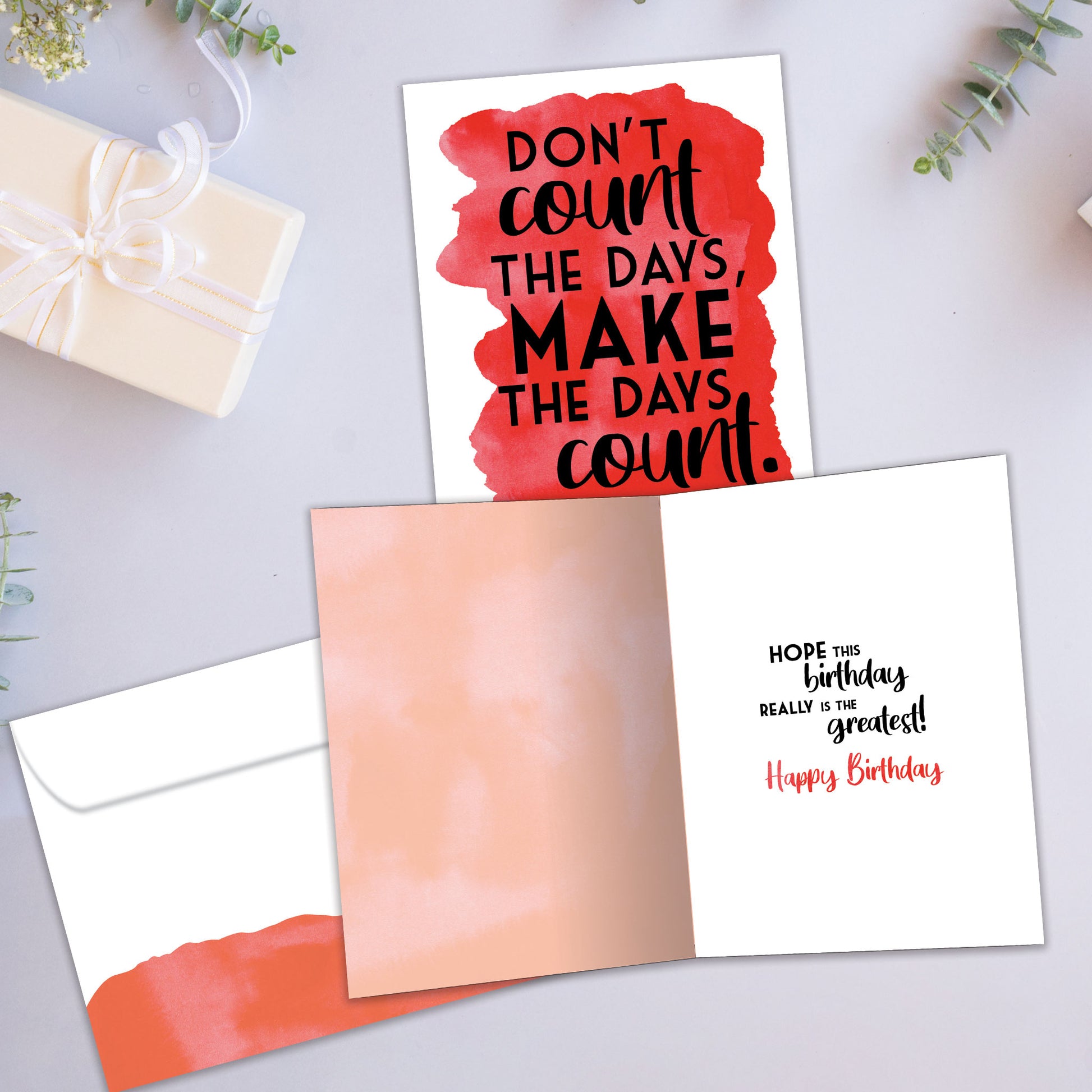Front and inside view of a Birthday greeting card showcasing the words "don't count the days, make the days count" on a red background, with a matching envelope.