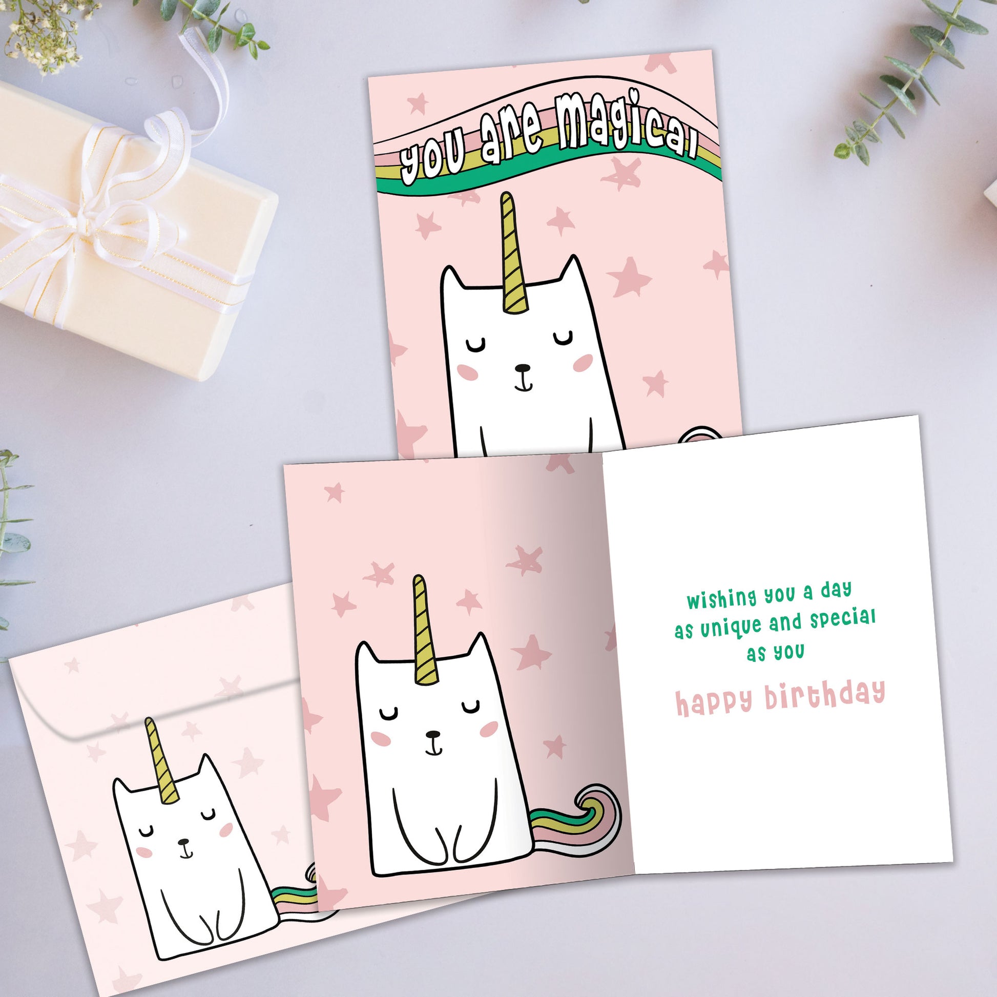 Front and inside view of a Birthday greeting card showcasing a unicorn cat with the words "you are magical" on a pink background, with a matching envelope.