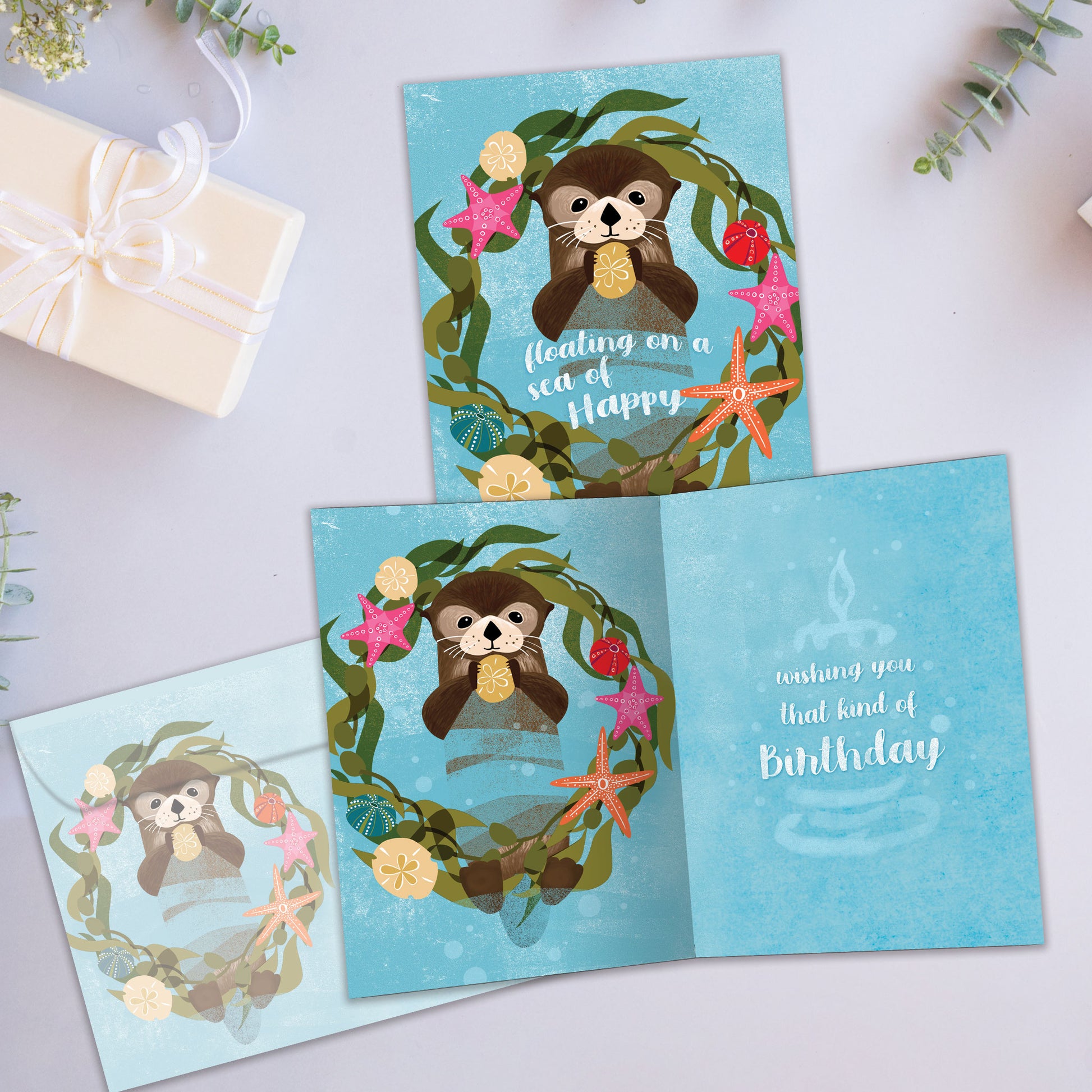 Front and inside view of a Birthday greeting card showcasing a floating sea otter with a happy message, with a matching envelope.