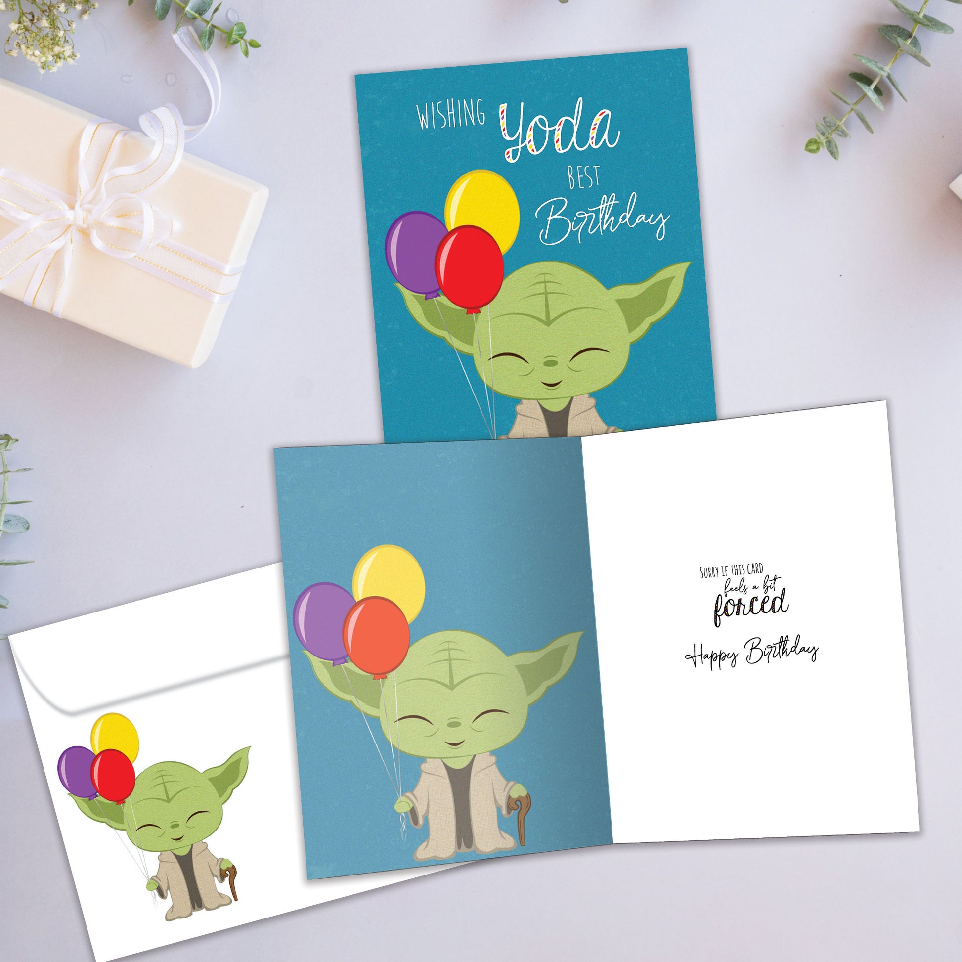 Front and inside view of a Birthday greeting card showcasing an illustration of Yoda holding balloons with a birthday message, with a matching envelope.