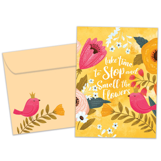 Front view of a Birthday greeting card featuring a bright floral design with a message about smelling the flowers, with a matching envelope.