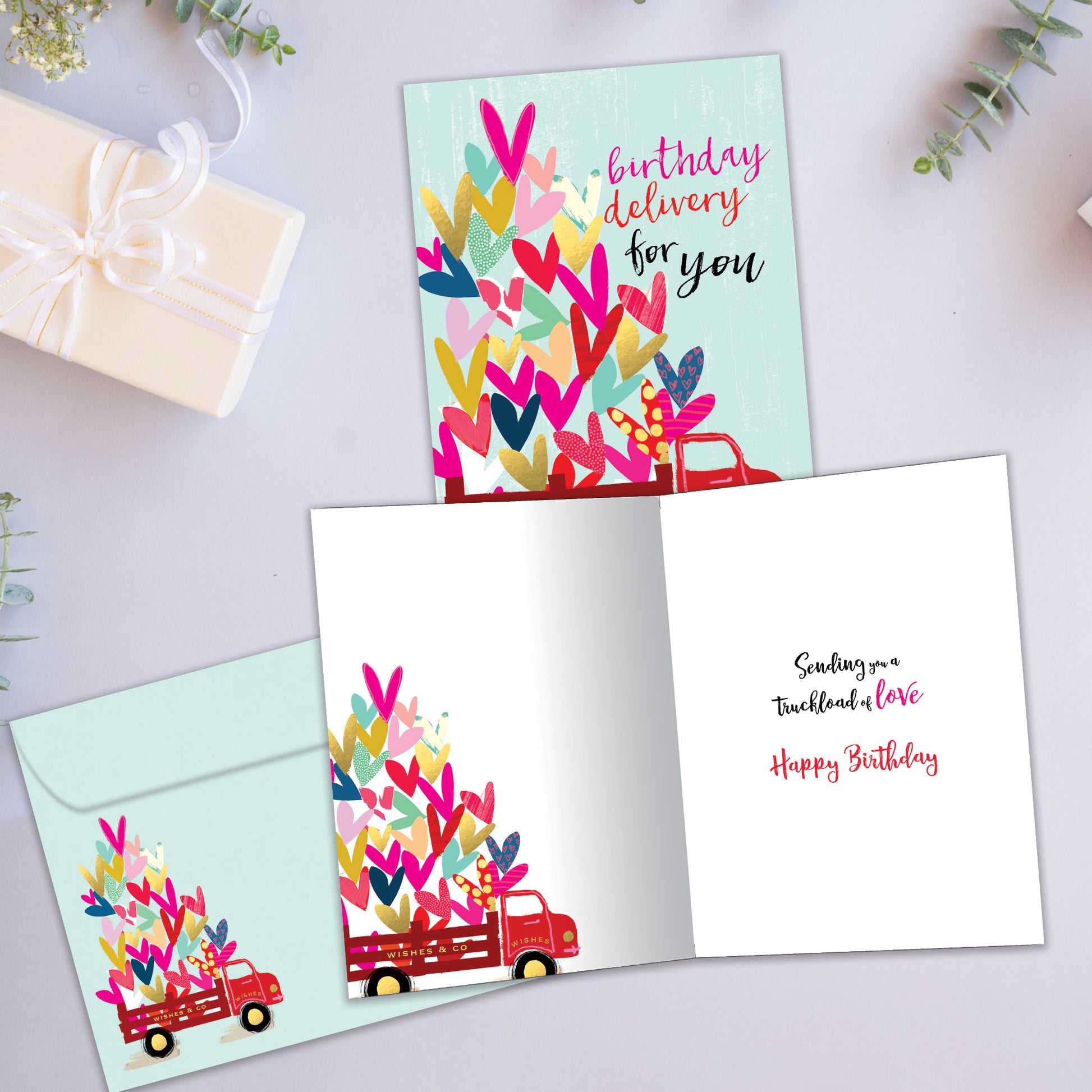 Front and inside view of a Birthday greeting card showcasing an illustration of a delivery truck filled with hearts, with a matching envelope.