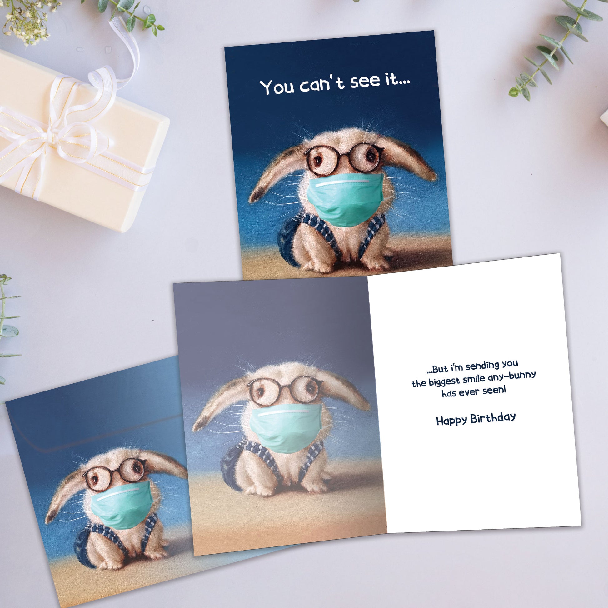 Front and inside view of a Birthday greeting card showcasing a bunny wearing a medical mask with the words "You can't see it...", with a matching envelope.