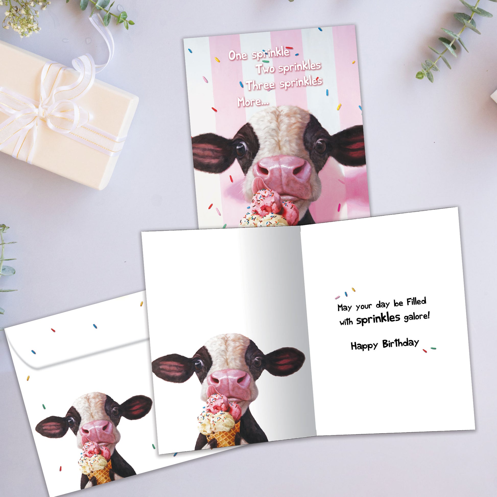 Front and inside view of a Birthday greeting card showcasing a cow licking an ice cream cone on a pinkish background, with a matching envelope.