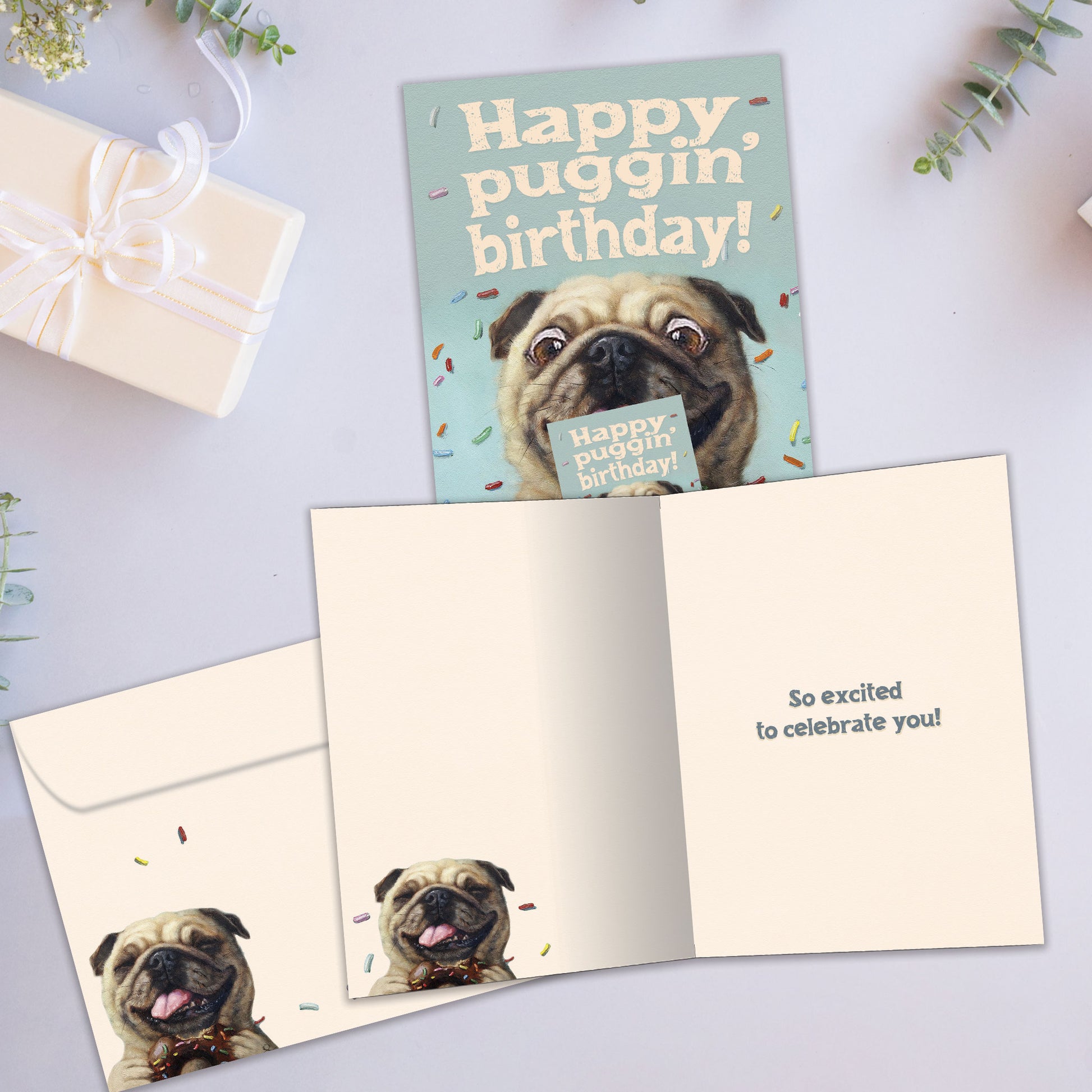 Front and inside view of a Birthday greeting card showcasing a playful dog design with the message "happy puggin' birthday", with a matching envelope.