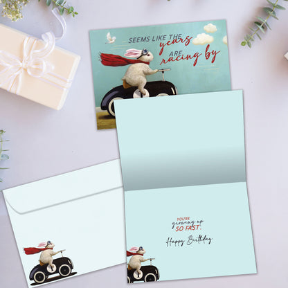 Front and inside view of a Birthday greeting card showcasing a bunny in a car design with the message "the years racing by", with a matching envelope.
