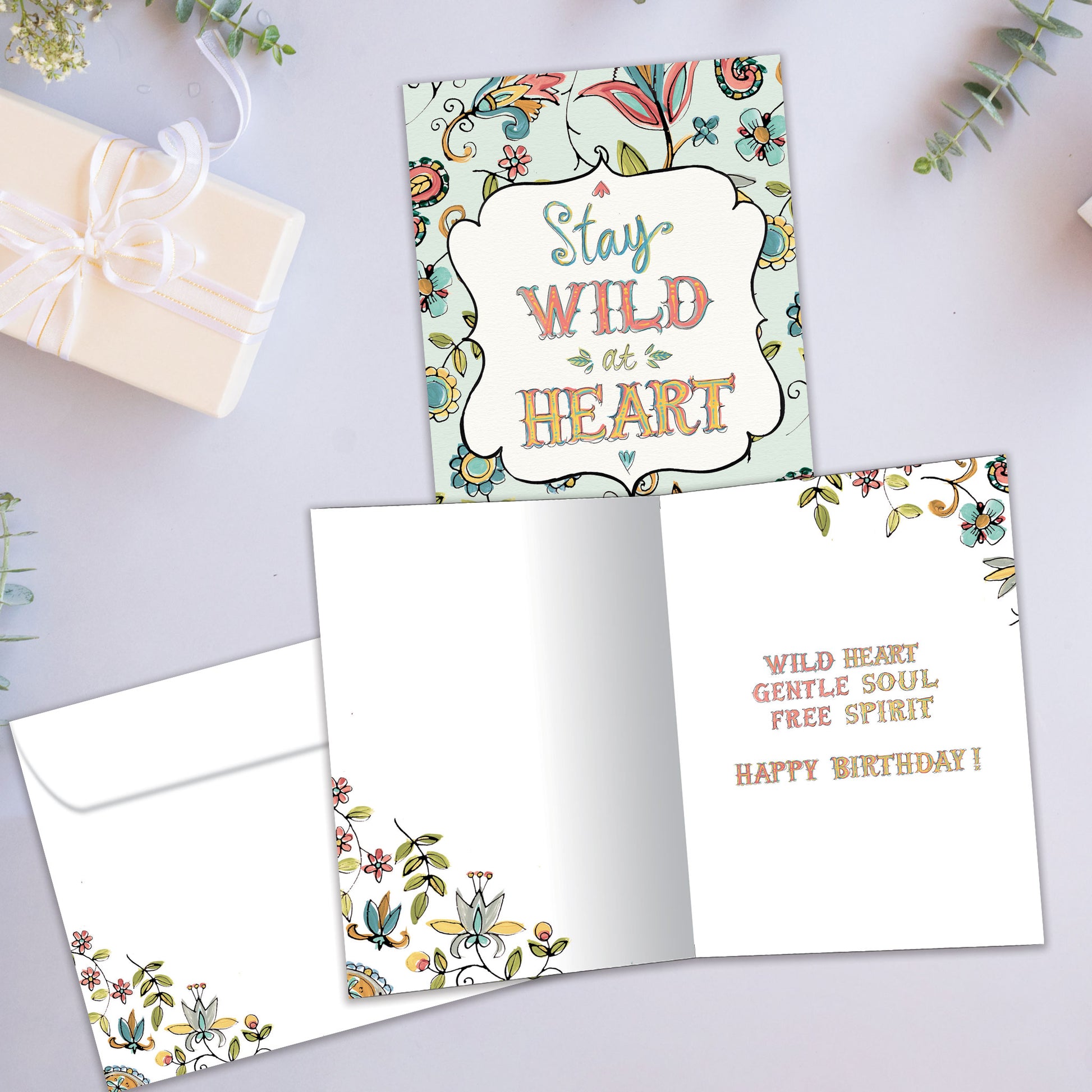 Front and inside view of a Birthday greeting card showcasing a floral design surrounding the words "stay wild at heart", with a matching envelope.