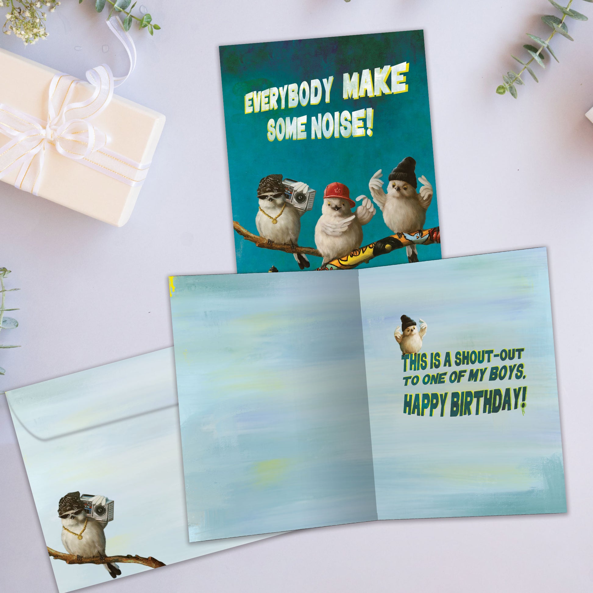 Front and inside view of a Birthday greeting card showcasing 3 hip-looking birds holding a ghetto blaster with the words "everybody make some noise", with a matching envelope.