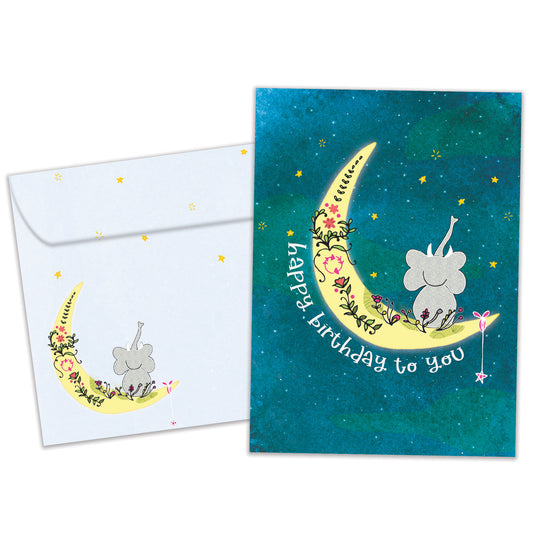 Front view of a Birthday greeting card featuring an elephant sitting on the moon crescent with a happy birthday message, with a matching envelope.