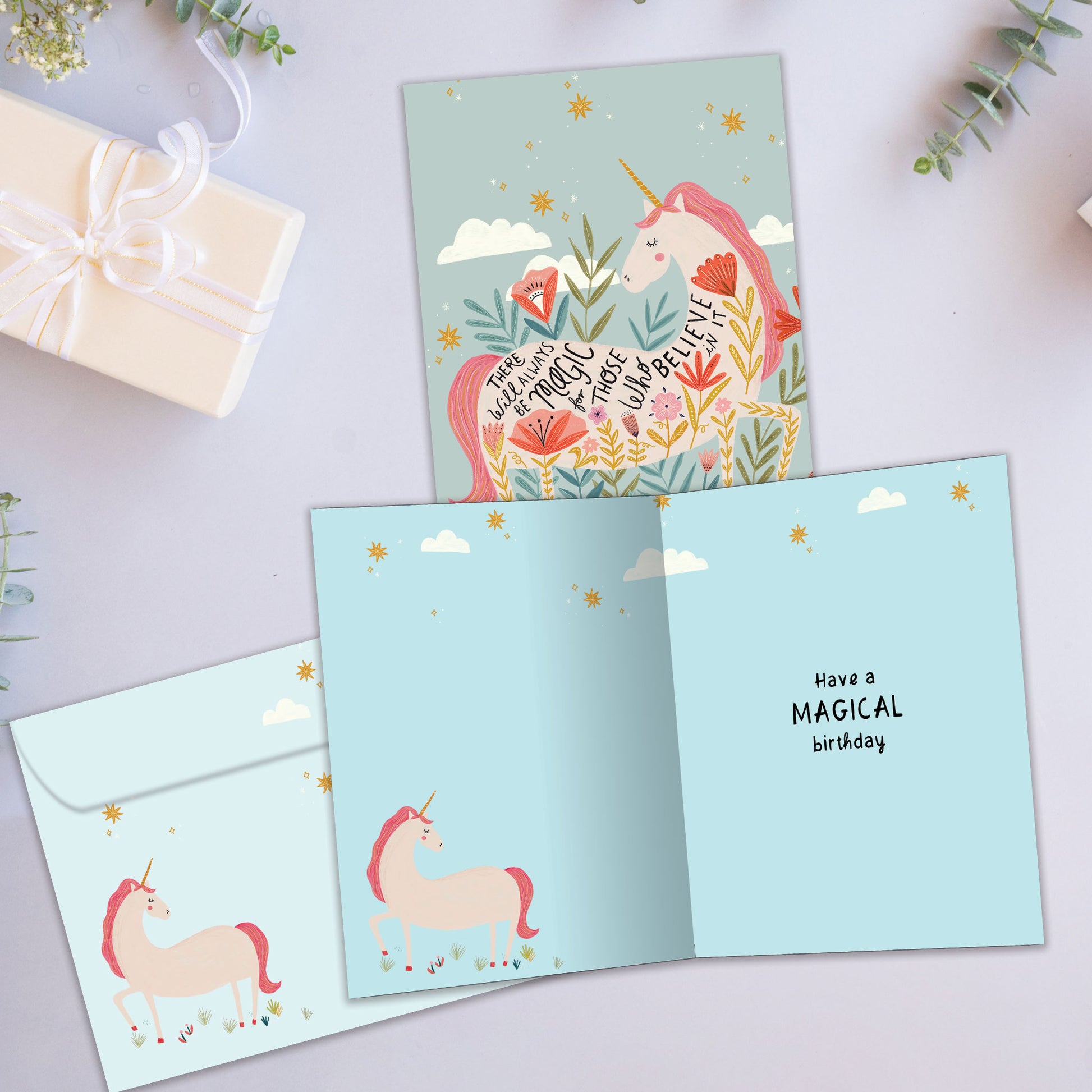 Front and inside view of a Birthday greeting card showcasing a pink unicorn with a magical message about believing, with a matching envelope.