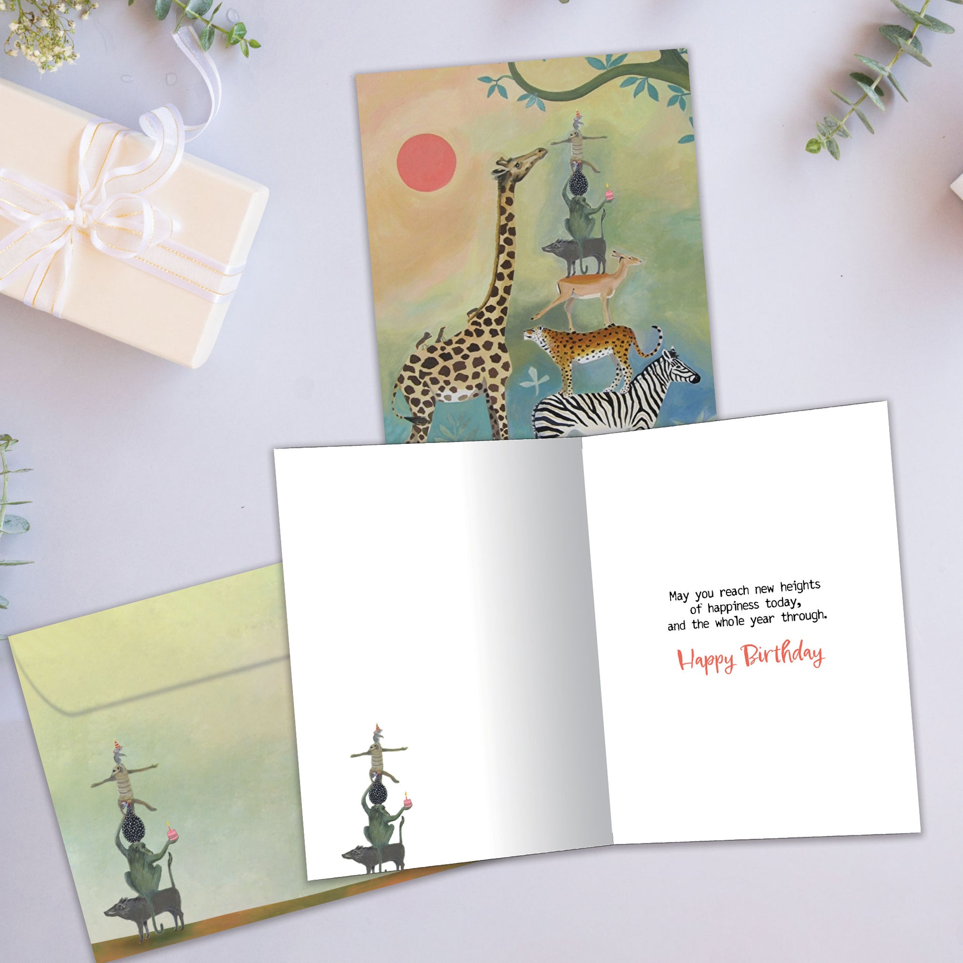 Front and inside view of a Birthday greeting card showcasing animals standing on each other next to a giraffe, with a matching envelope.