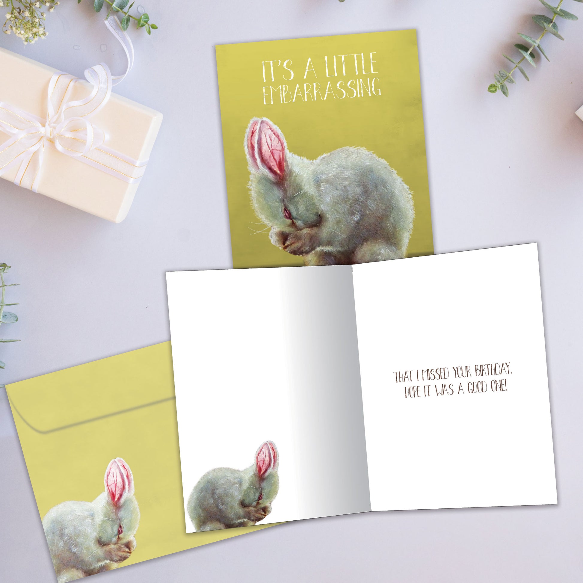 Front and inside view of a Birthday greeting card showcasing a bunny covering its face with the message "It's a little embarrassing", with a matching envelope.