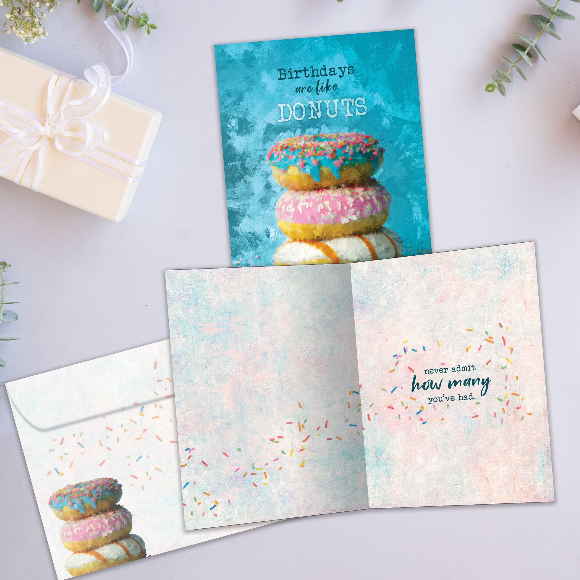 Front and inside view of a Birthday greeting card showcasing a stack of donuts with the message "birthdays are like donuts", with a matching envelope.