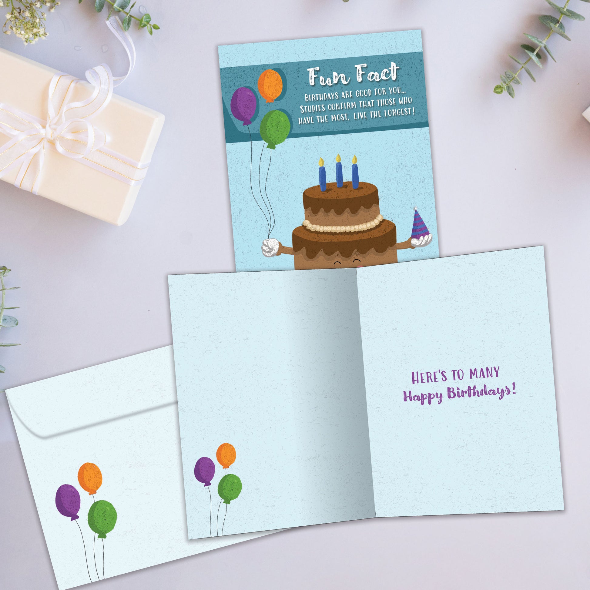 Front and inside view of a Birthday greeting card showcasing a smiling cake with a fun fact message, with a matching envelope.
