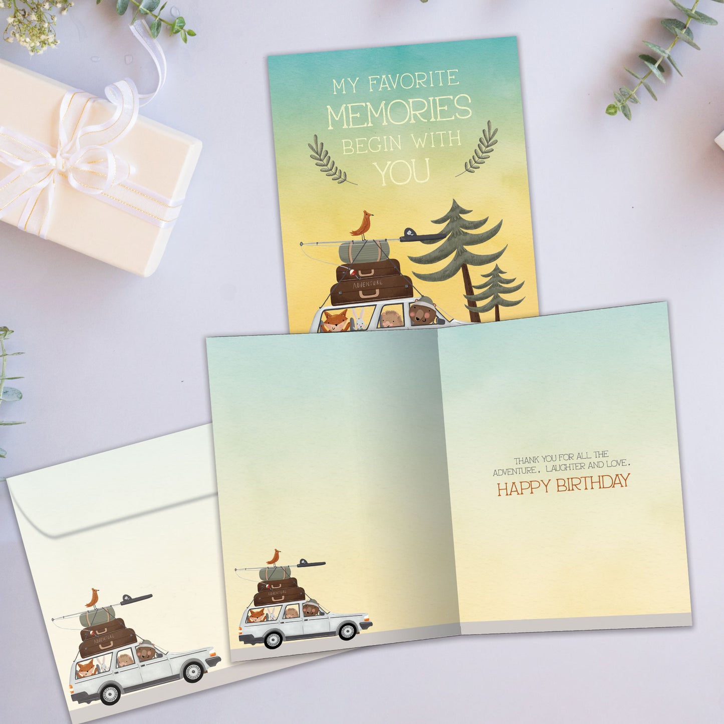 Front and inside view of a Birthday greeting card showcasing an animal family in a car going on a camping vacation with a message about memories, with a matching envelope.