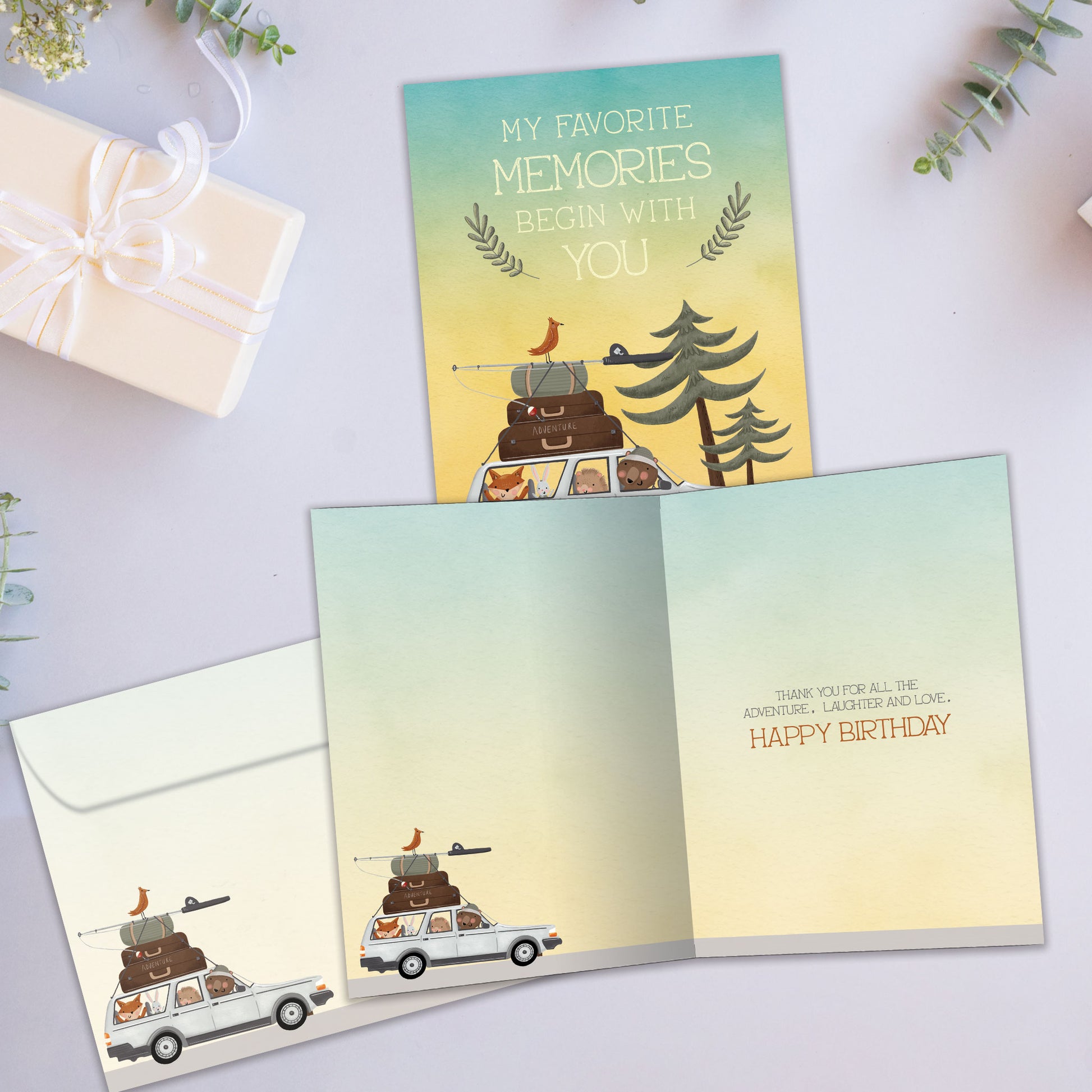 Front and inside view of a Birthday greeting card showcasing an animal family in a car going on a camping vacation with a message about memories, with a matching envelope.