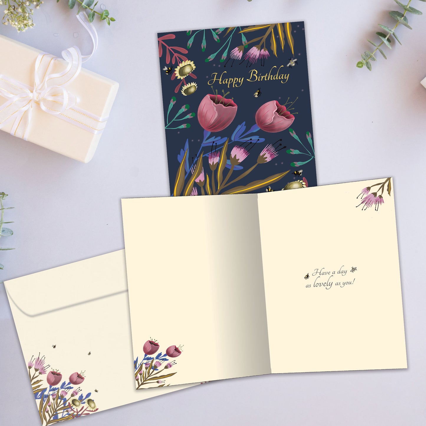 Front and inside view of a Birthday greeting card showcasing "happy birthday" surrounded by flowers on a dark background, with a matching envelope.