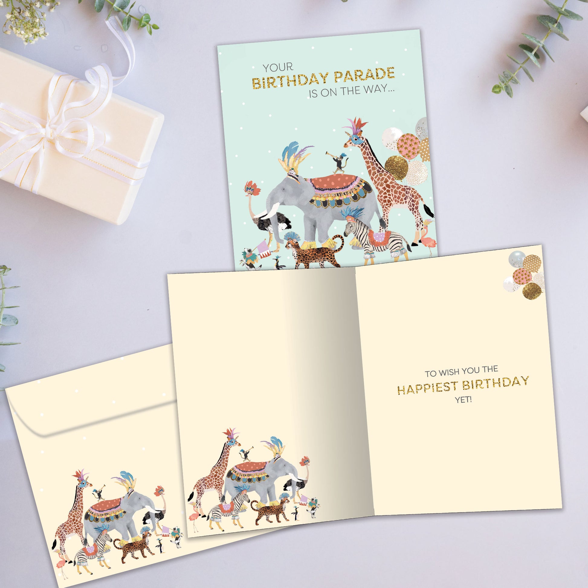 Front and inside view of a Birthday greeting card showcasing an illustration of animals parading with a message, with a matching envelope.