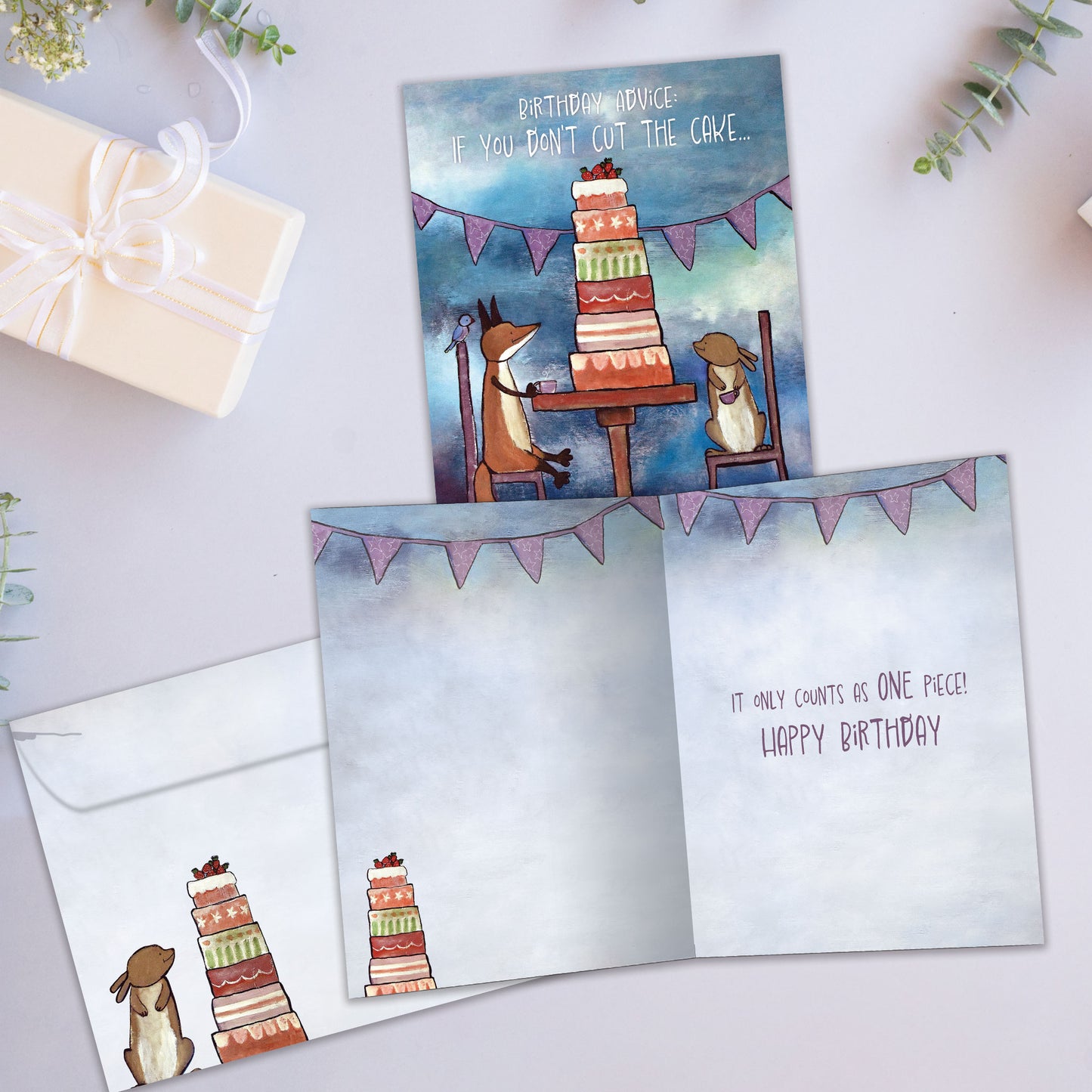 Front and inside view of a Birthday greeting card showcasing animals sitting at a table with a tall birthday cake and a message about cutting the cake, with a matching envelope.