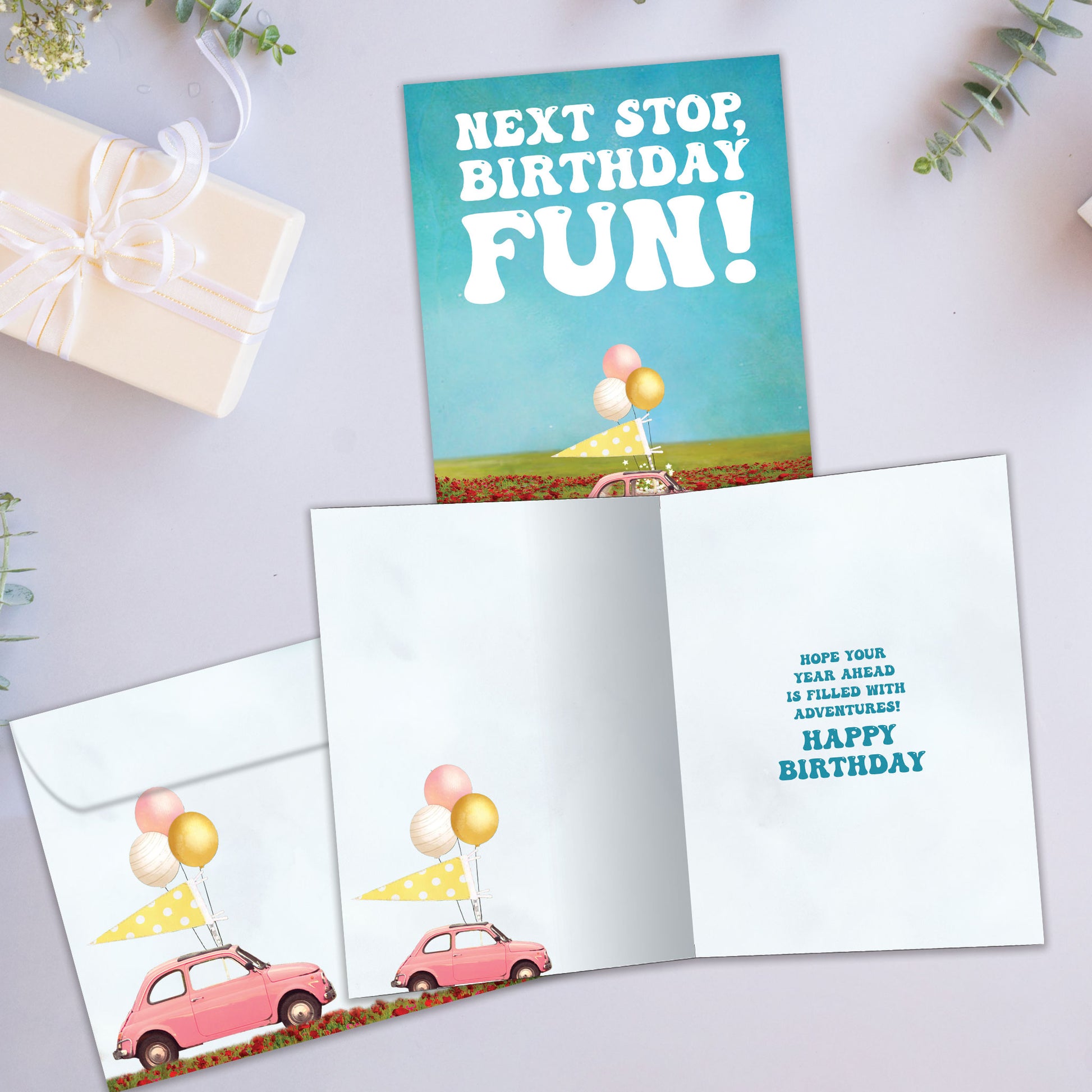 Front and inside view of a Birthday greeting card showcasing a car decorated with balloons and the message "next stop, birthday fun!", with a matching envelope.