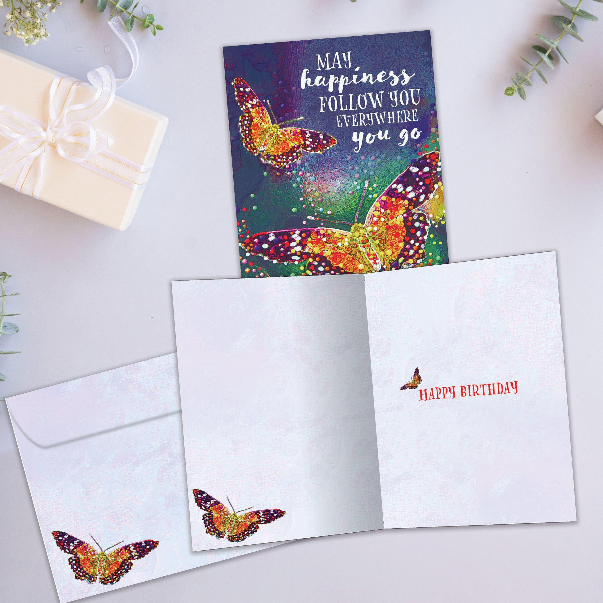 Front and inside view of a birthday greeting card showcasing an illustration of two colourful butterflies with a message about happiness, with a matching envelope.