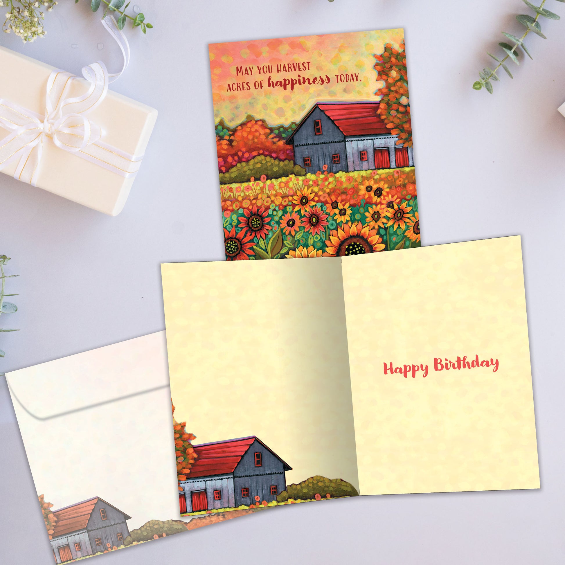 Front and inside view of a birthday greeting card showcasing an illustration of a barn and sunflowers in brilliant autumn colours with a heartfelt message, with a matching envelope.