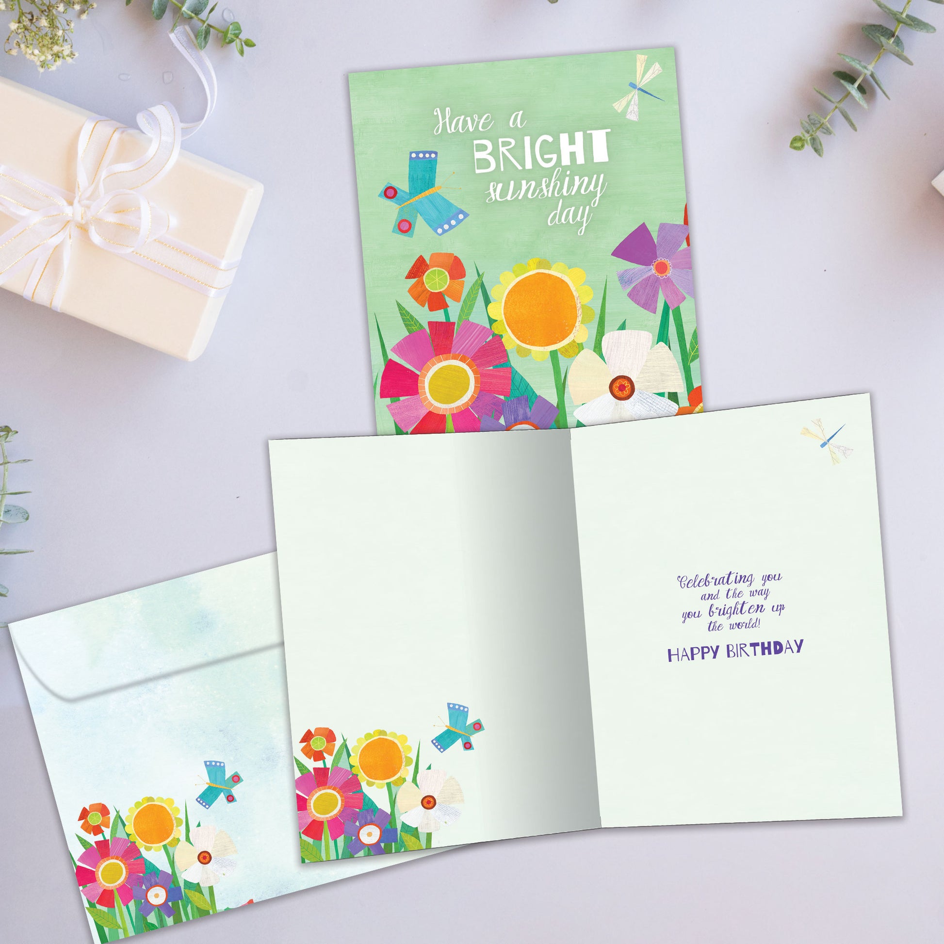 Front and inside view of a birthday greeting card showcasing the message "have a bright sunshiny day" surrounded by flowers, with a matching envelope.