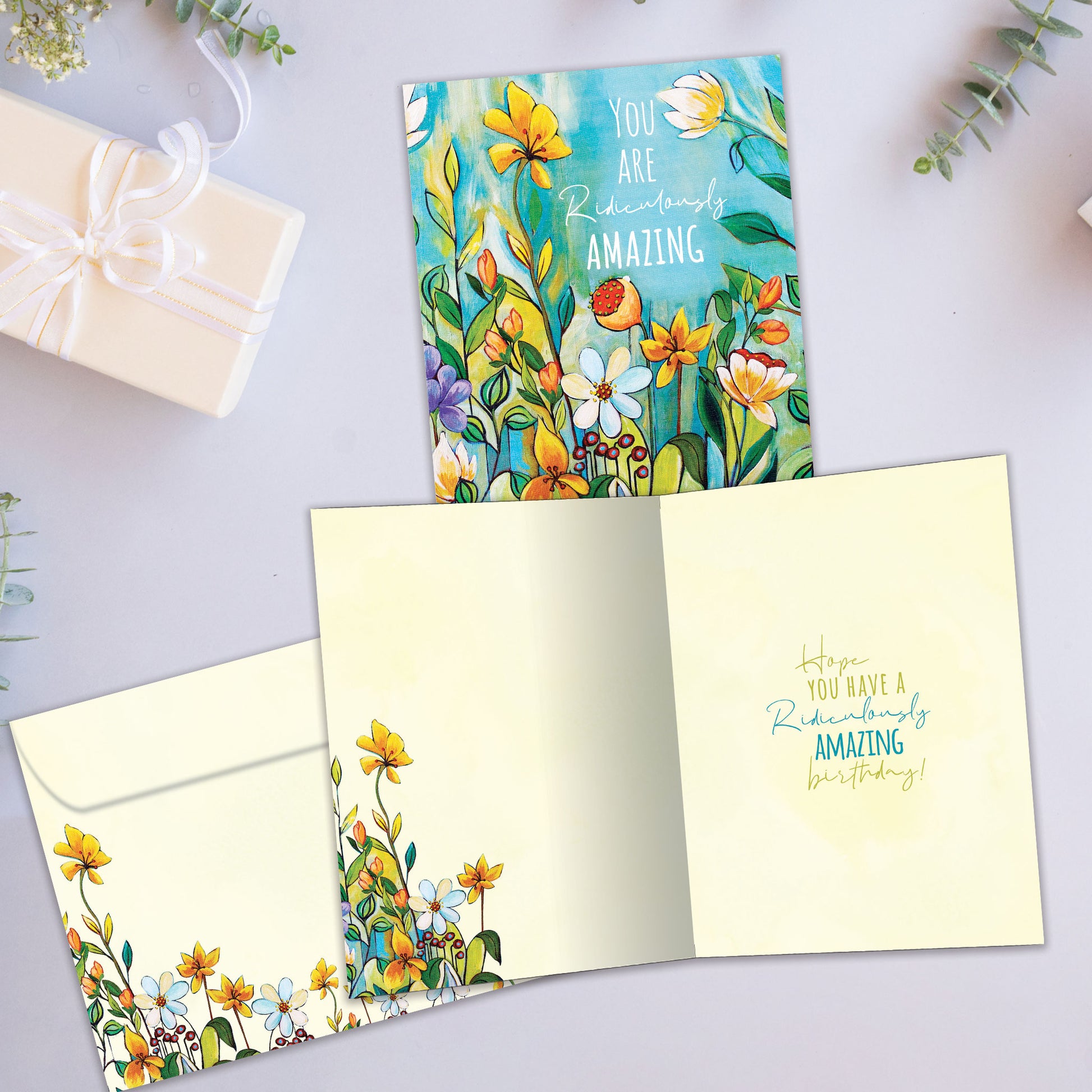 Front and inside view of a birthday greeting card showcasing the message "you are ridiculously amazing" surrounded by vibrant flowers, with a matching envelope.
