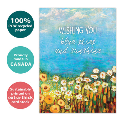 Front view of a birthday greeting card with the message "wishing you blue skies and sunshine" and an illustration of blue skies and flowers, highlighting its eco-friendly materials and made in Canada.