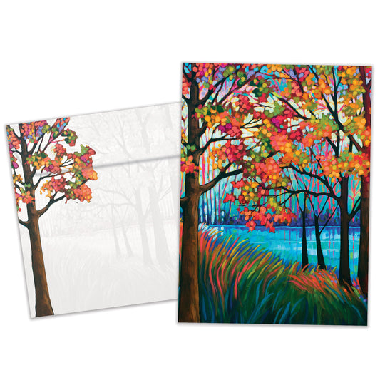 Front view of a birthday greeting card featuring a vibrant illustration of fall trees and a shimmering lake, with a matching envelope.