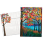 Front view of a birthday greeting card featuring a vibrant illustration of fall trees and a shimmering lake, with a matching envelope.