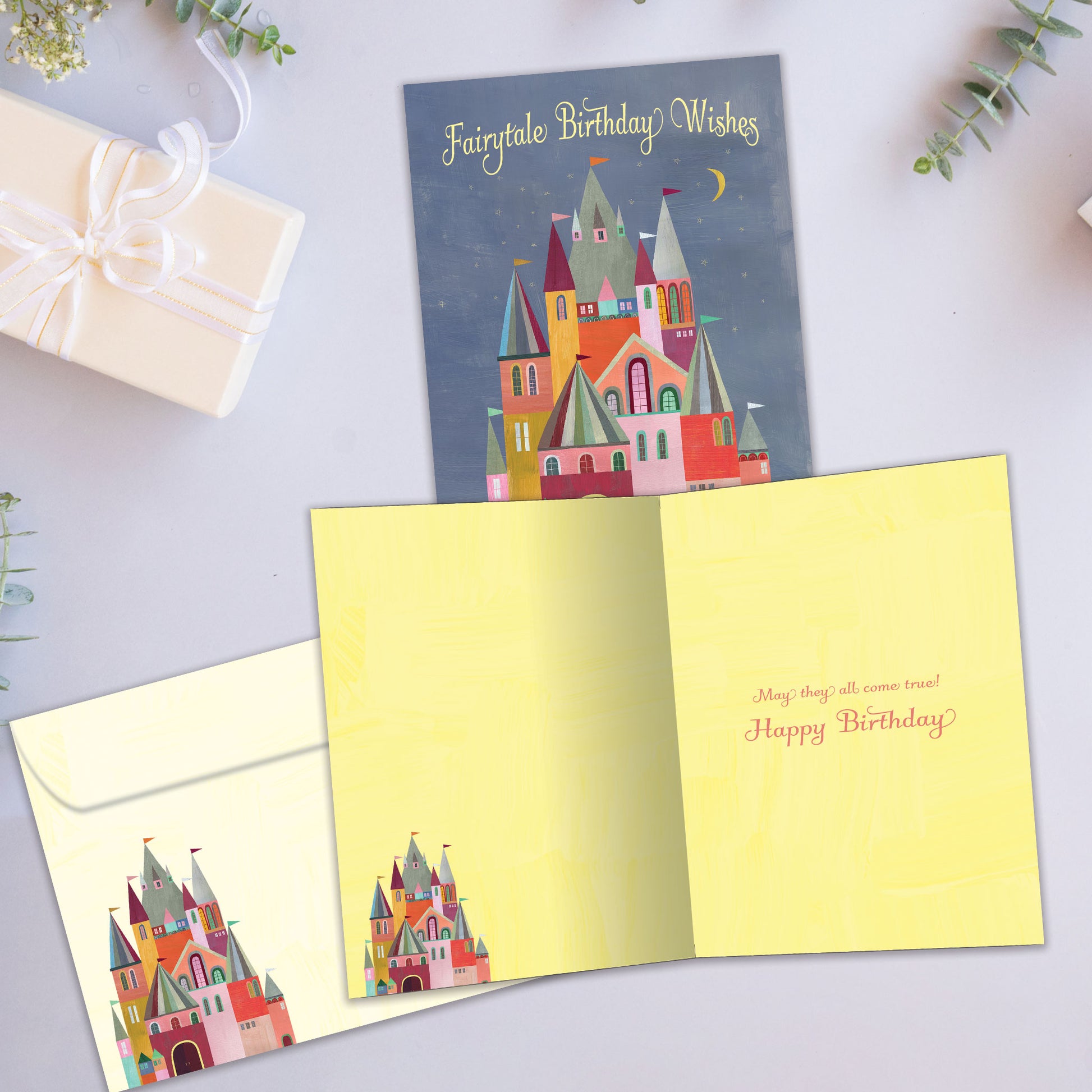Front and inside view of a birthday greeting card showcasing a colourful illustration of a castle with the words "Fairytale Birthday Wishes", with a matching envelope.