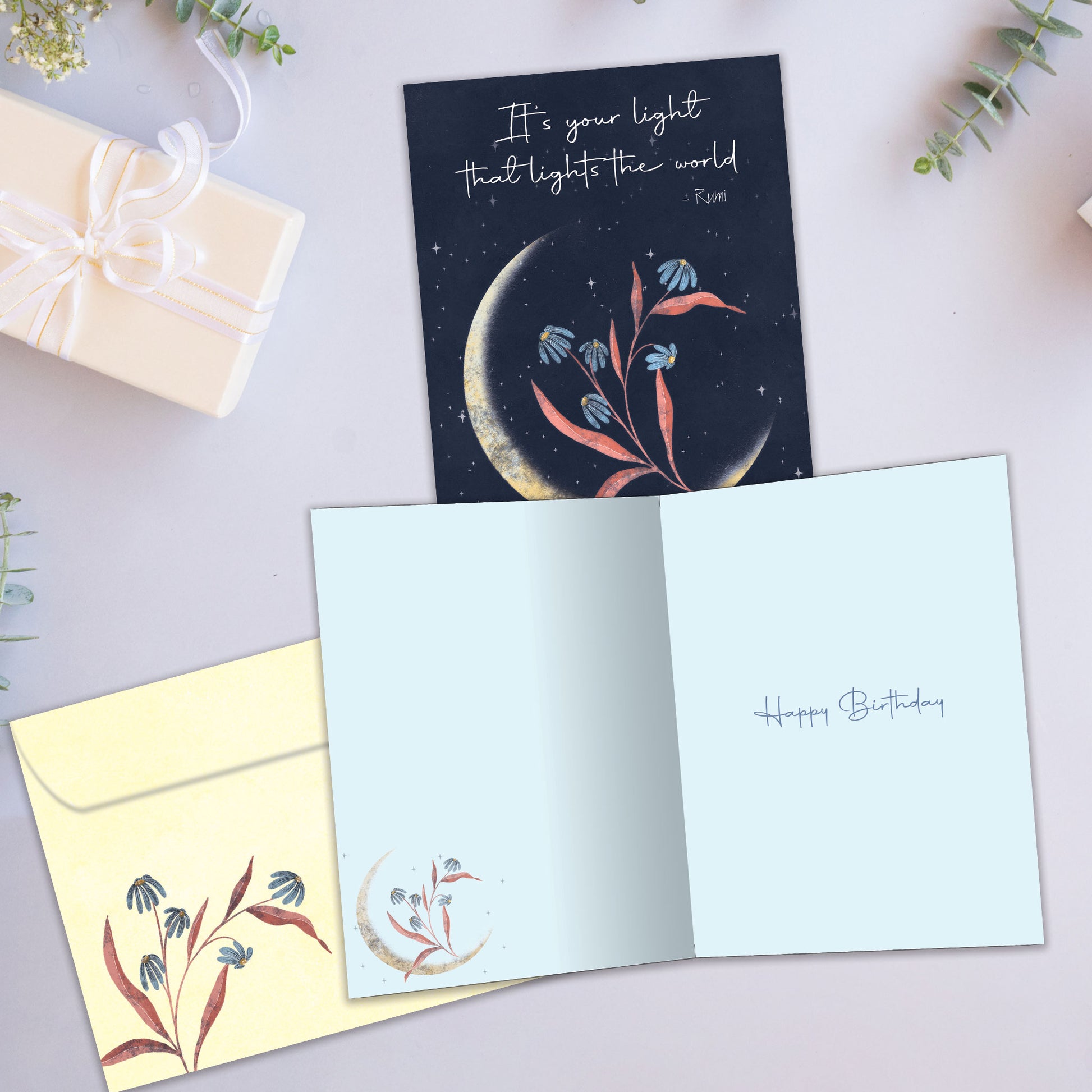 Front and inside view of a birthday greeting card showcasing an illustration of a crescent moon with flowers and a beautiful message, with a matching envelope.