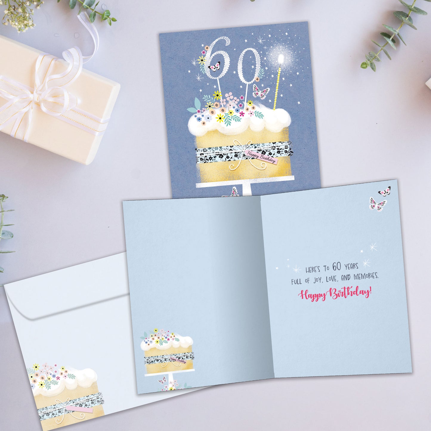 Front and inside view of a Birthday greeting card showcasing a birthday cake with 60 candles on a blue background, with a matching envelope.