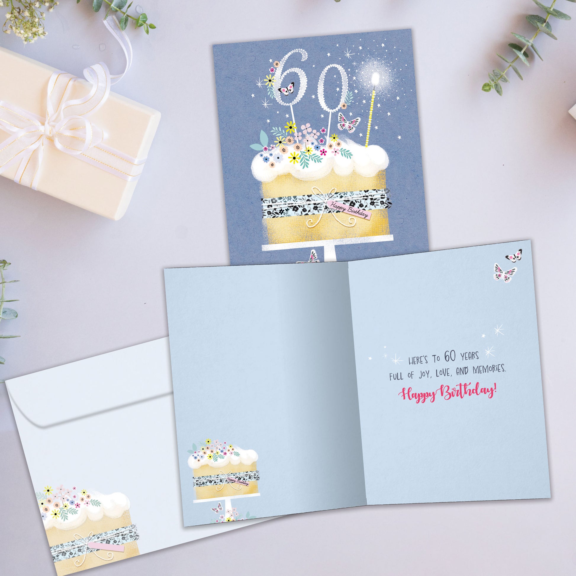 Front and inside view of a Birthday greeting card showcasing a birthday cake with 60 candles on a blue background, with a matching envelope.