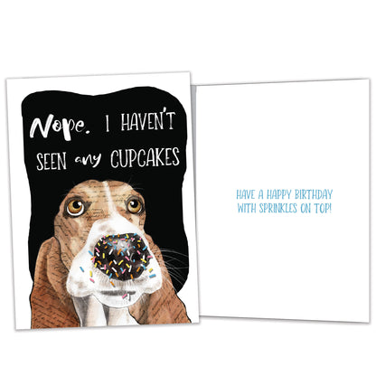 Front and inside view of a birthday greeting card featuring an illustration of a dog’s face denying eating the cupcakes, with matching design details inside.