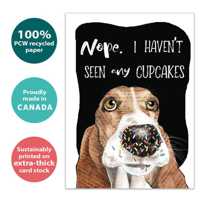 Front view of a birthday greeting card with an illustration of a dog’s face denying eating the cupcakes, highlighting its eco-friendly materials and made in Canada.