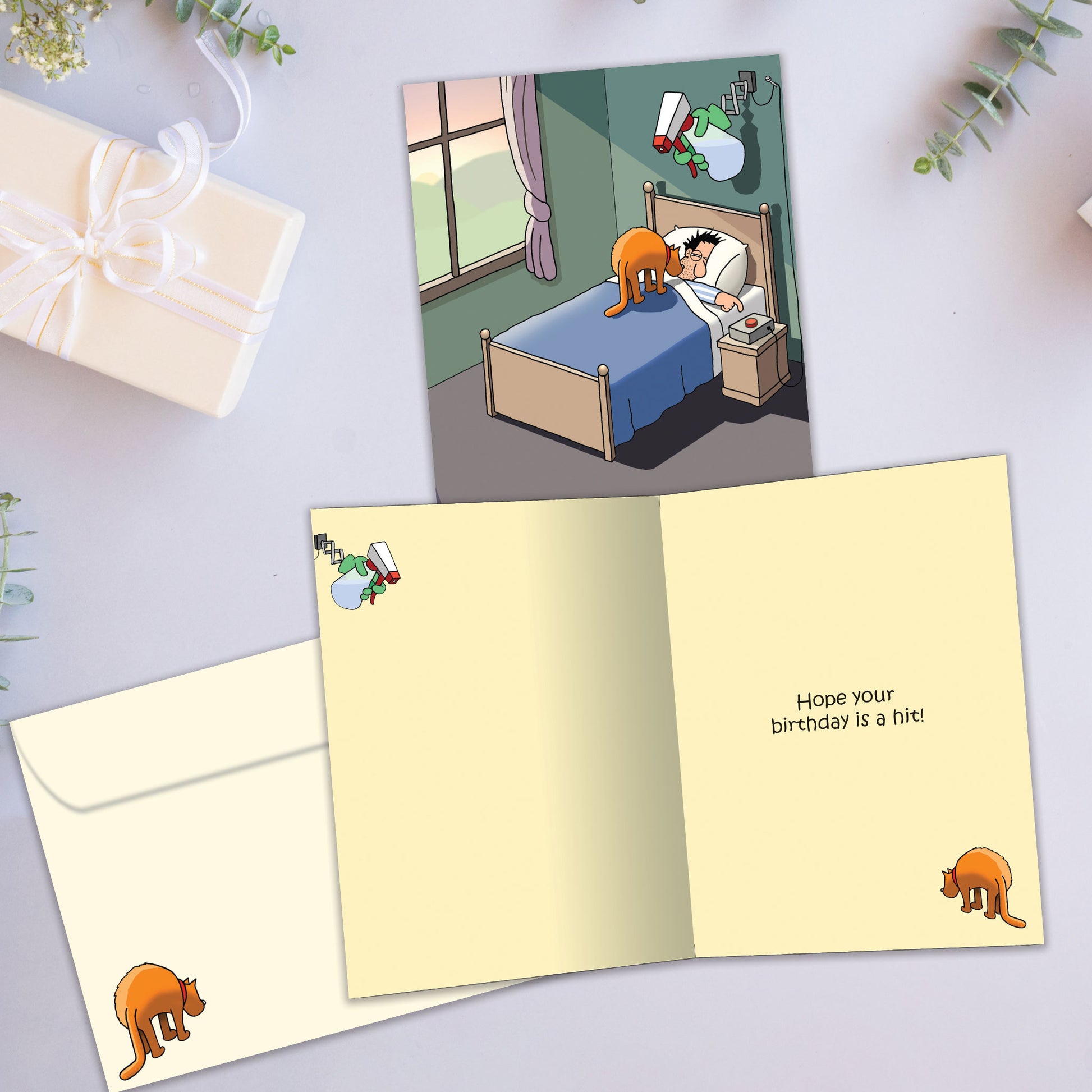 Front and inside view of a Birthday greeting card showcasing a cat waking up its owner and the message “Snooze buttons for cat owners”, with a matching envelope