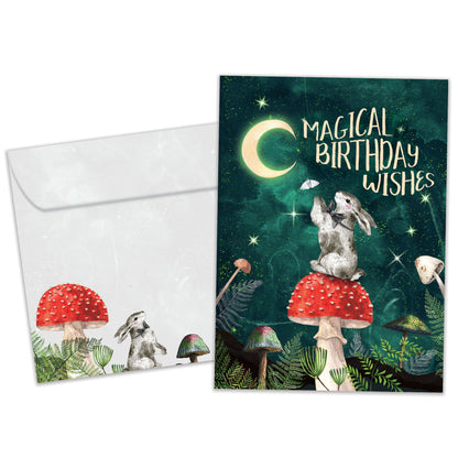 Front view of a Birthday greeting card featuring a bunny sitting on a mushroom under the moon and a birthday messsage, with a matching envelope