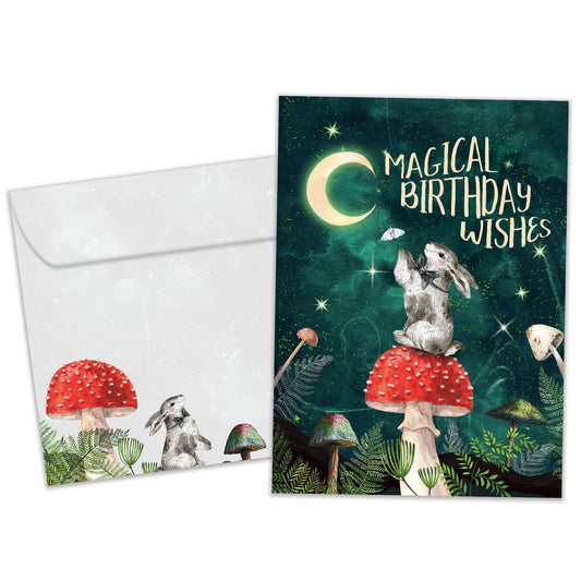 Front view of a Birthday greeting card featuring a bunny sitting on a mushroom under the moon and a birthday messsage, with a matching envelope