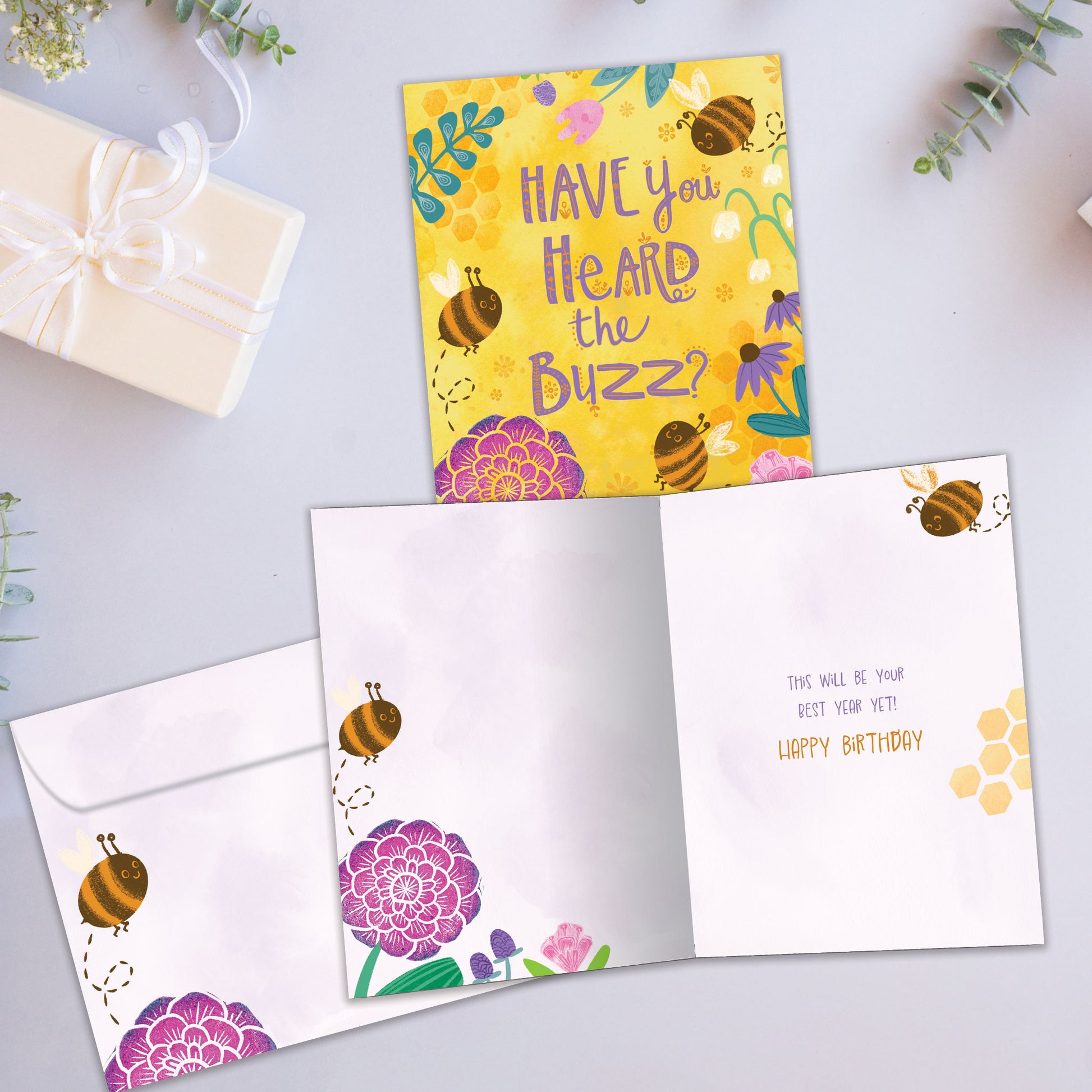 Front and inside view of a Birthday greeting card showcasing bees and flowers with the message "Have you heard the buzz?", with a matching envelope.